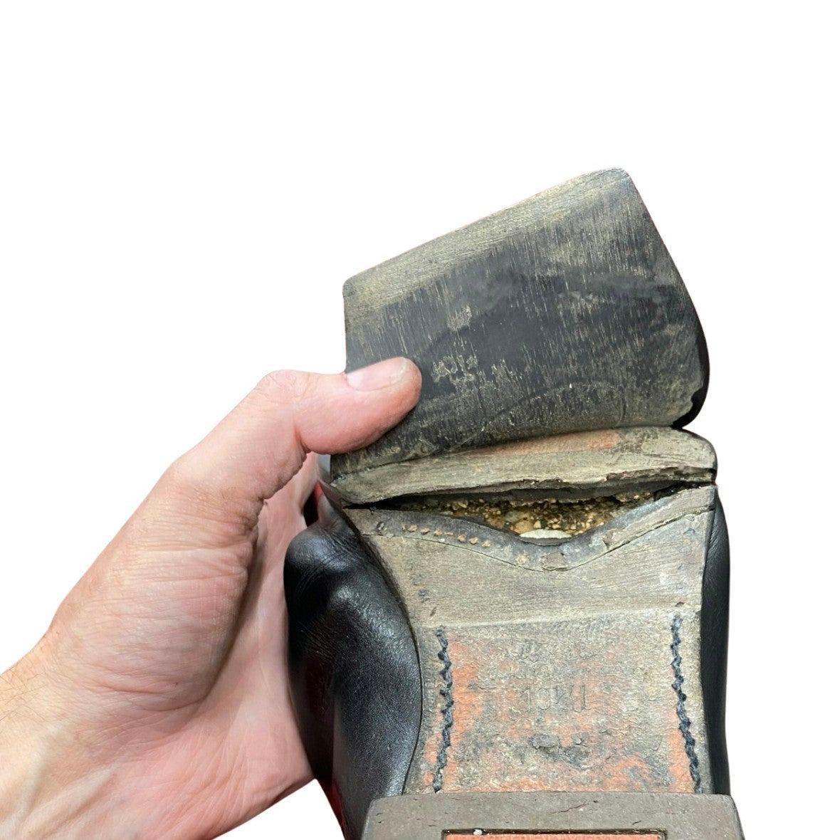 R.M. Williams boot with a broken sole, held by a hand on a white background.